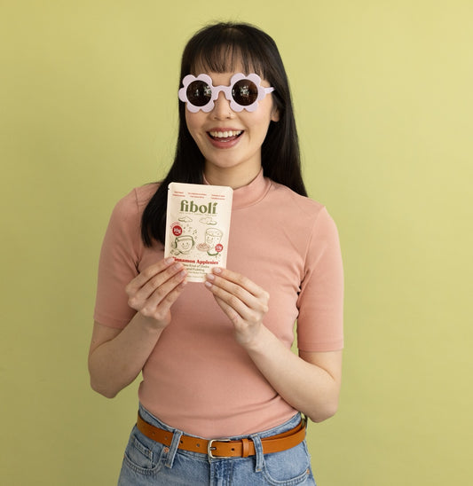 Woman holding a fiboli pouchbranding against a green background